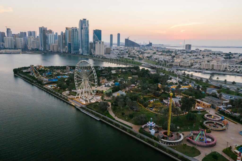 Stunning aerial shot of Al Montazah Parks with a view of Sharjah's skyline at sunset.